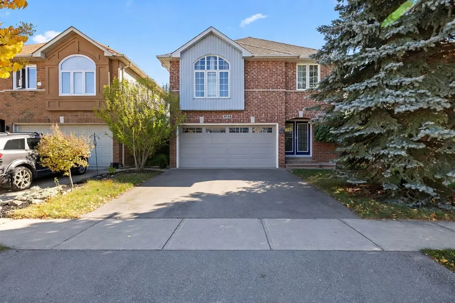 4114 Pincay Oaks Lane, Burlington — the two-storey brick home with its double garage and blue spruce